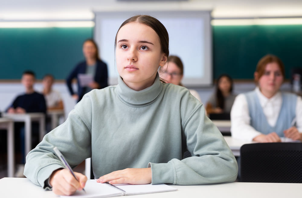 Female student sit at desk and makes notes