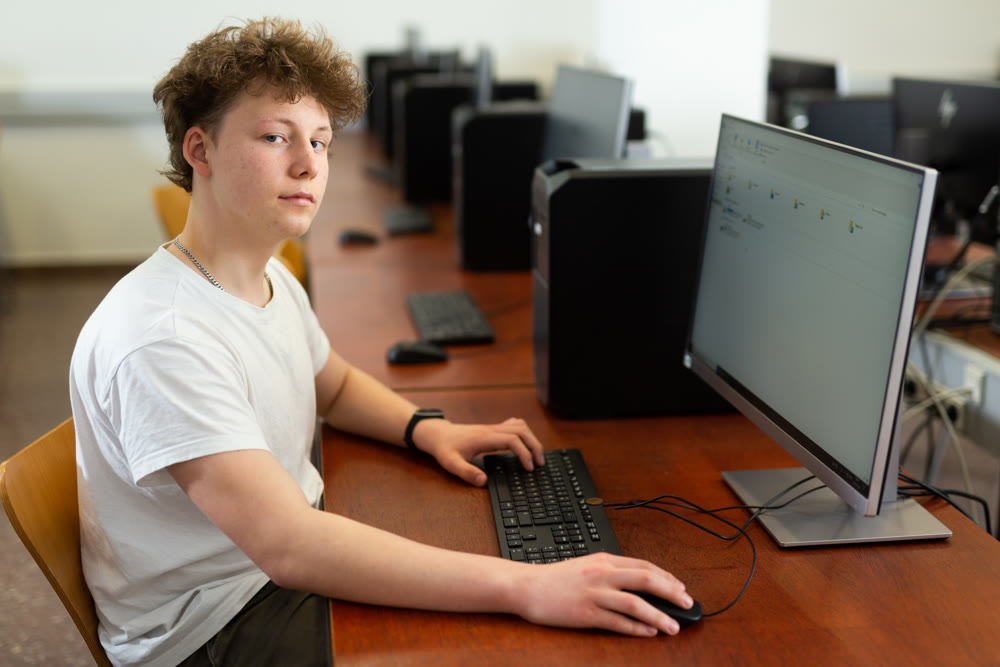 Teenager boy using PC during computer science lesson