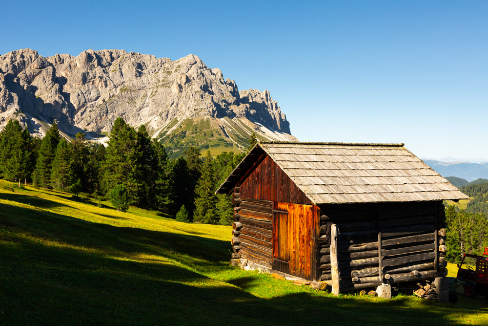 Wooden farm building on hillside in Dolomites.