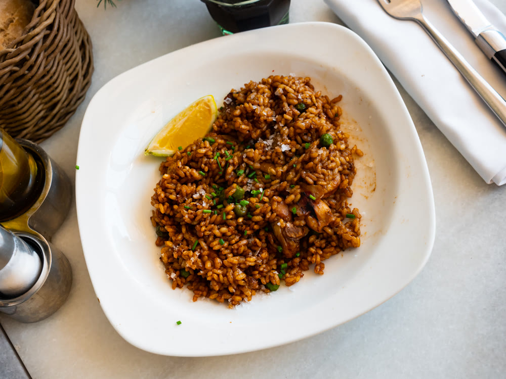 Plate is filled with paella made according to Spanish recipe from rice cereals, seafood, and chicken