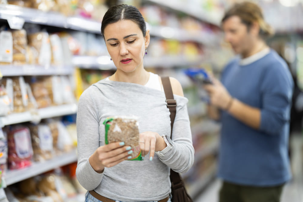 Adult woman choosing dry grains in grocery store