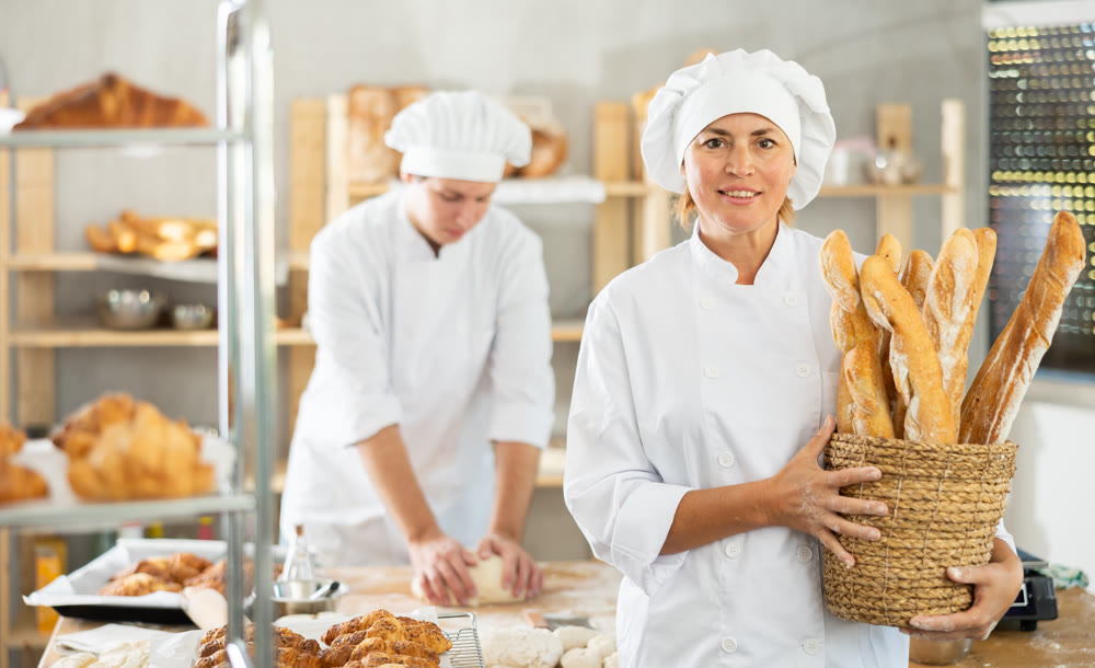 Adult woman baker with basket of baguettes