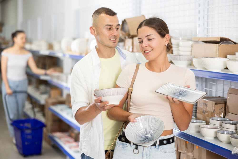 Interested young couple choosing ceramic plates in dishware store