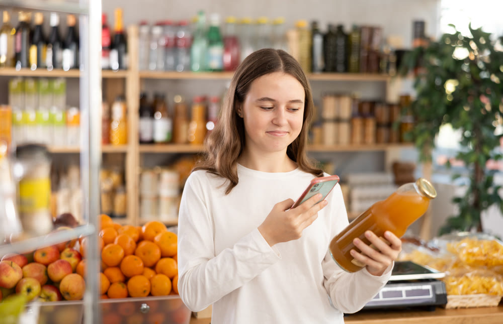 Teenage girl scanning qr code of peach juice