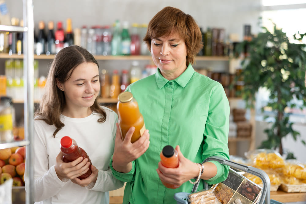 Mother and daughter choose tasty juice together in grocery section of supermarket
