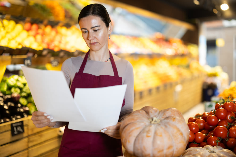 Middle-aged female seller restocking with paper in grocery market