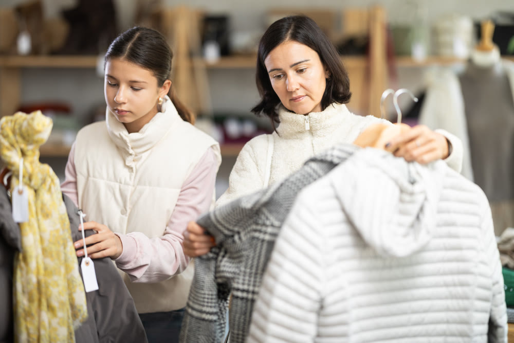 Adult woman and teenage girl choose coat or down jacket