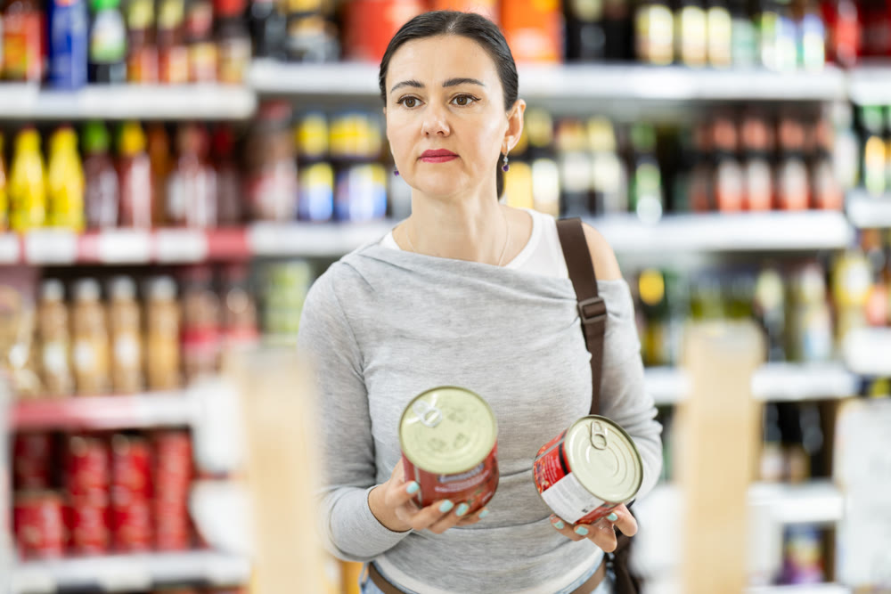 Adult woman chooses canned goods in store