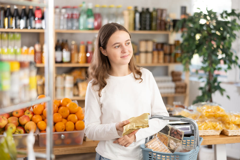 Teenage girl choosing nougat in grocery store