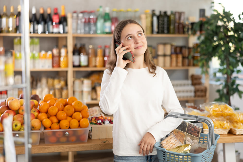Teenage girl choosing groceries while talking on phone