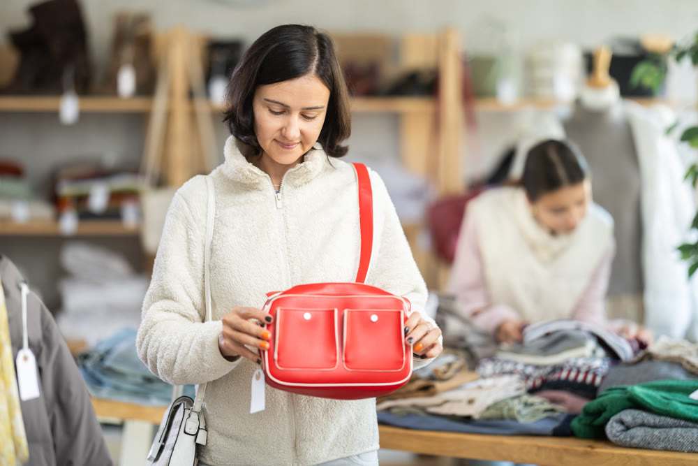 Woman looks at products in store and selects handbag.