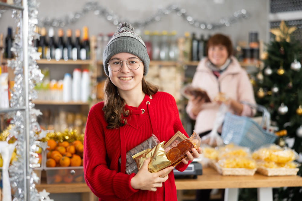 Adolescence girl customer choose consider desserts and sweet snacks, woman in background