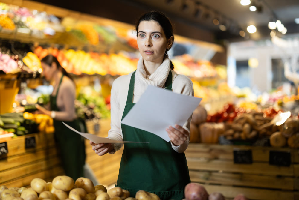Upset woman owner of greengrocer with paper document