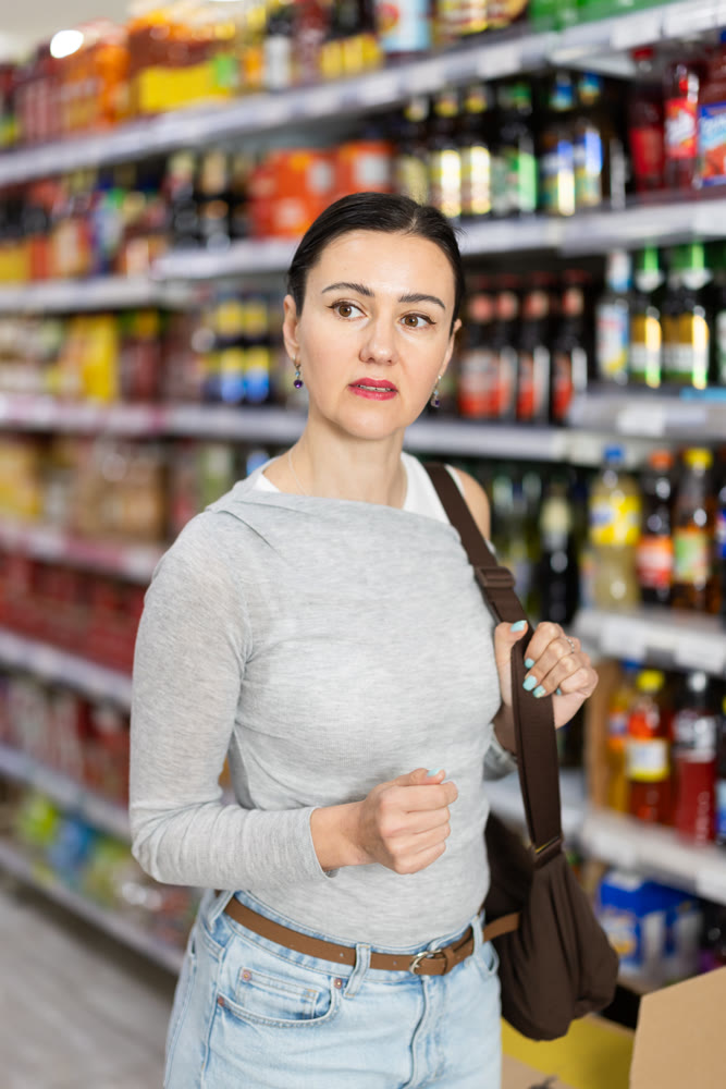 In food store, woman looking for something on shelf of showcase