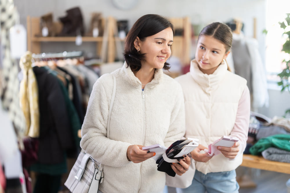 Mother and teen daughter looks at products in store and selects cotton socks.