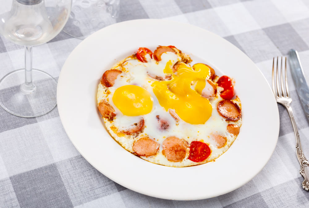 Fried eggs with tomato served with sausage