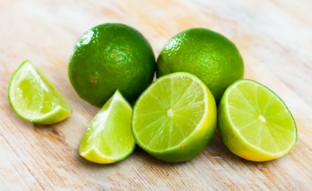 Whole and sliced limes on wooden table