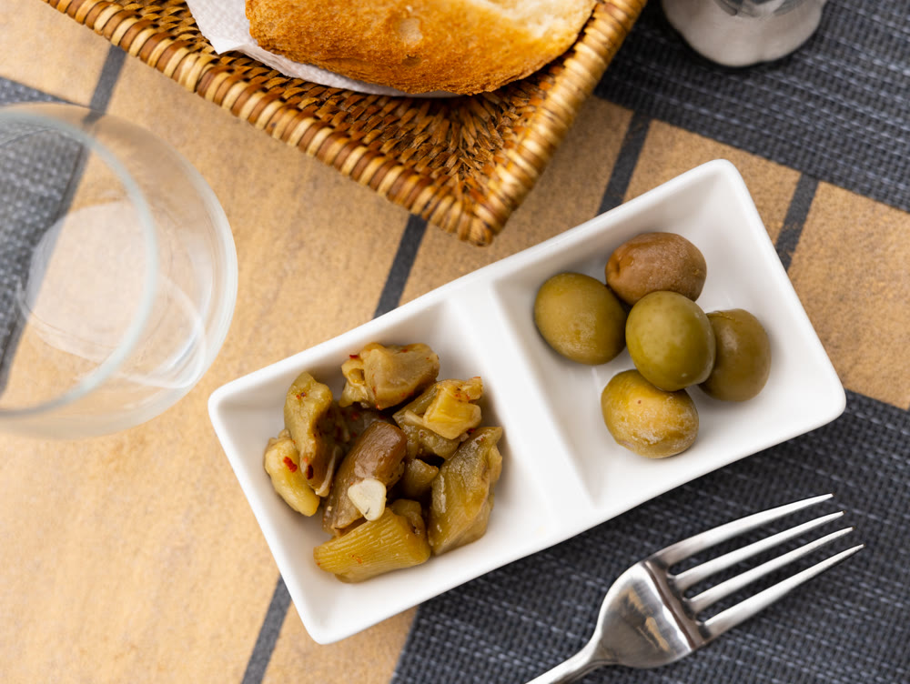 Pieces of pickled eggplant and green olives served as appetizer