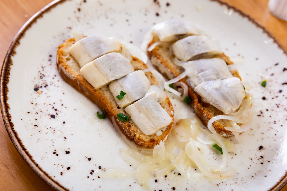 Marinated herring and onion sandwich served on plate