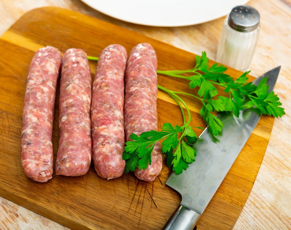 Fresh raw pork botifarra sausages ready on wooden cutting board