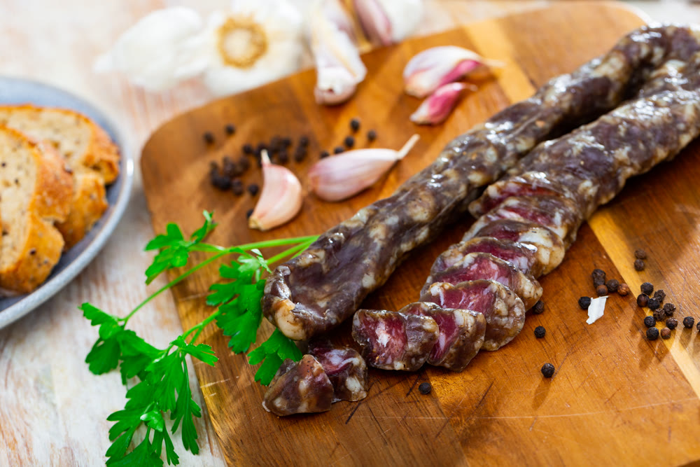 Dry pork sausage with condiments on table