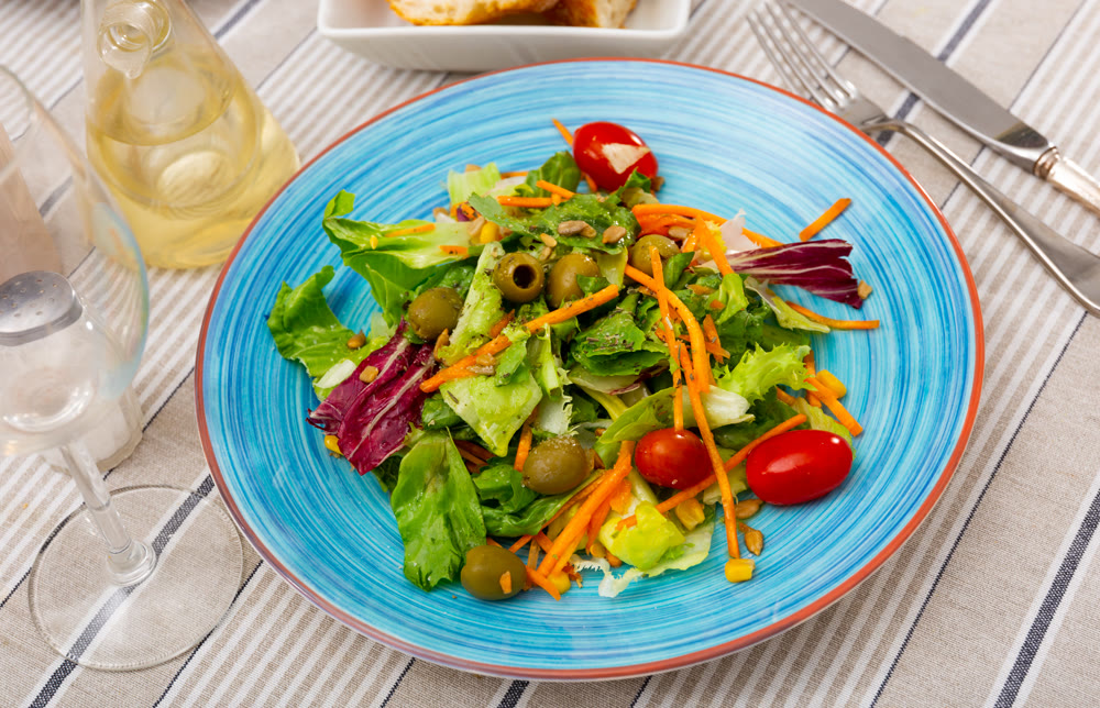 Plate contains portion of salad from fresh seasonal vegetables