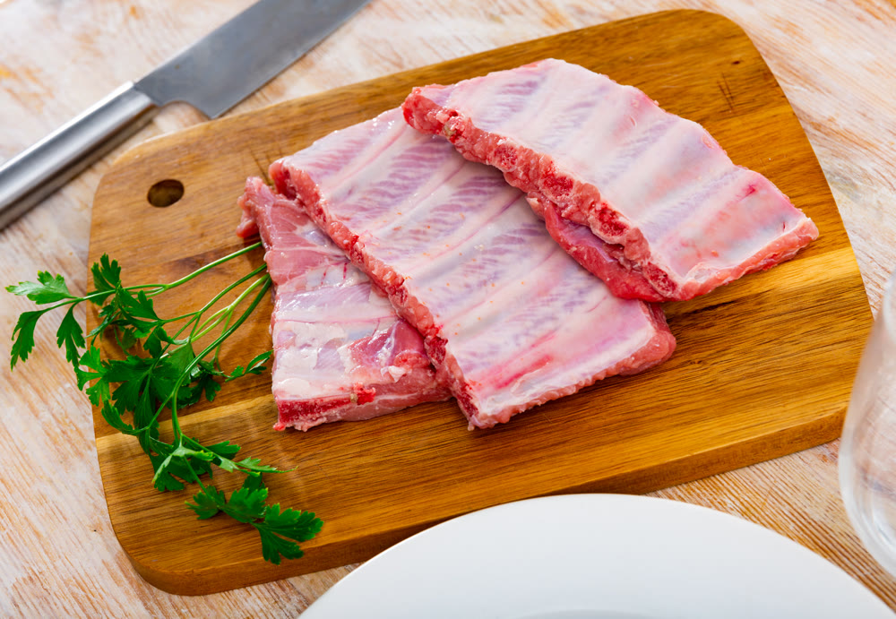Raw pork ribs with parsley on wooden table. Cooking food