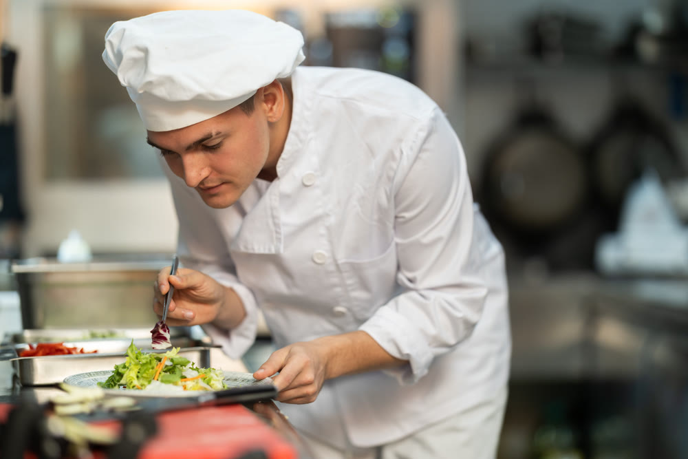 Young male chef with prepared dish in restaurant kitchen