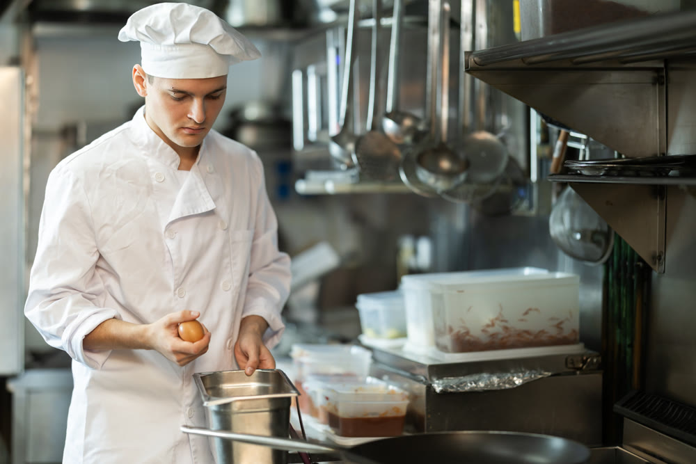 Young male chef prepares dish in restaurant kitchen