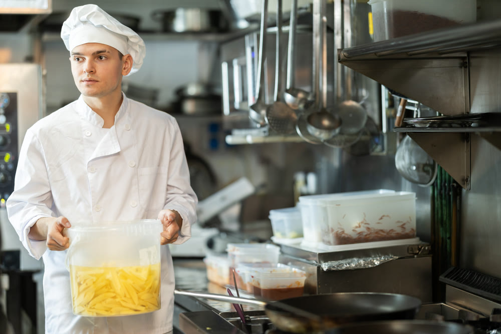Young male chef prepares potatoes in kitchen