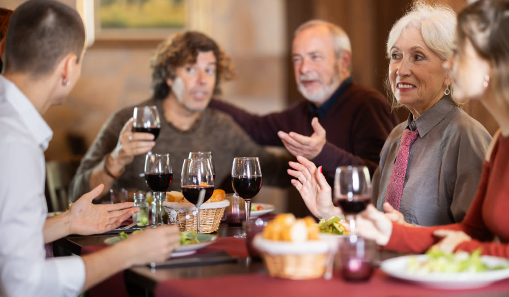 Large friendly family gathered at table to have lunch in restaurant