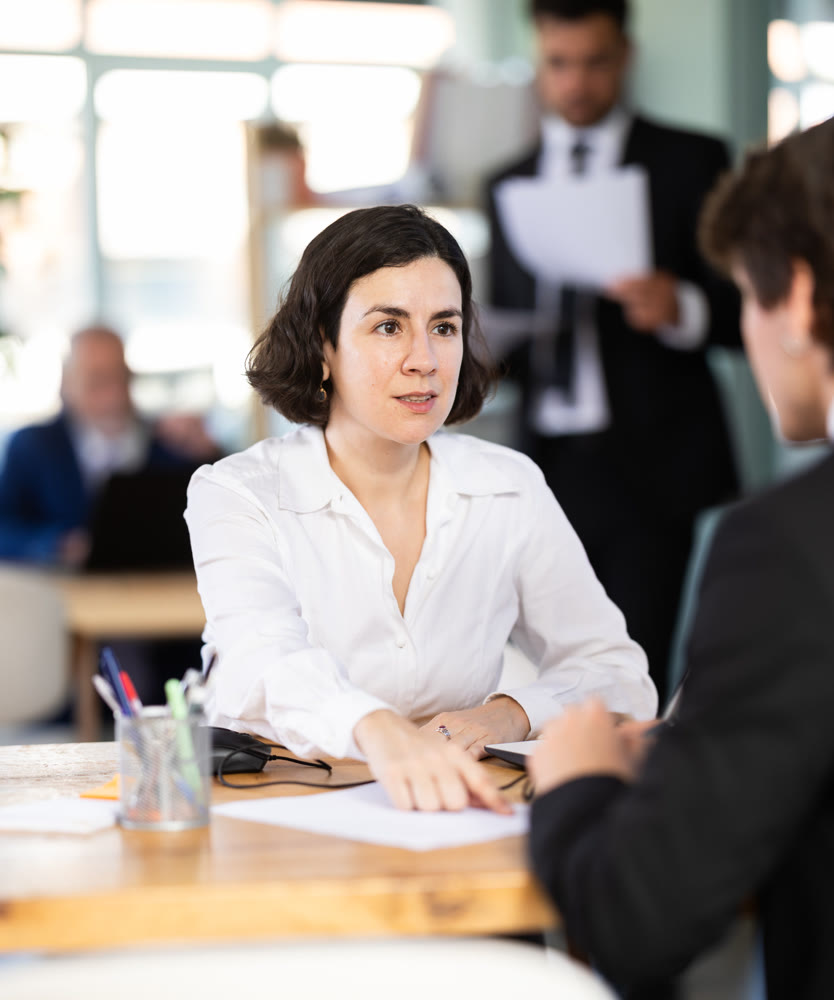 Professional young female lawyer or bank employee talking and signing loan agreement with man client in bank office