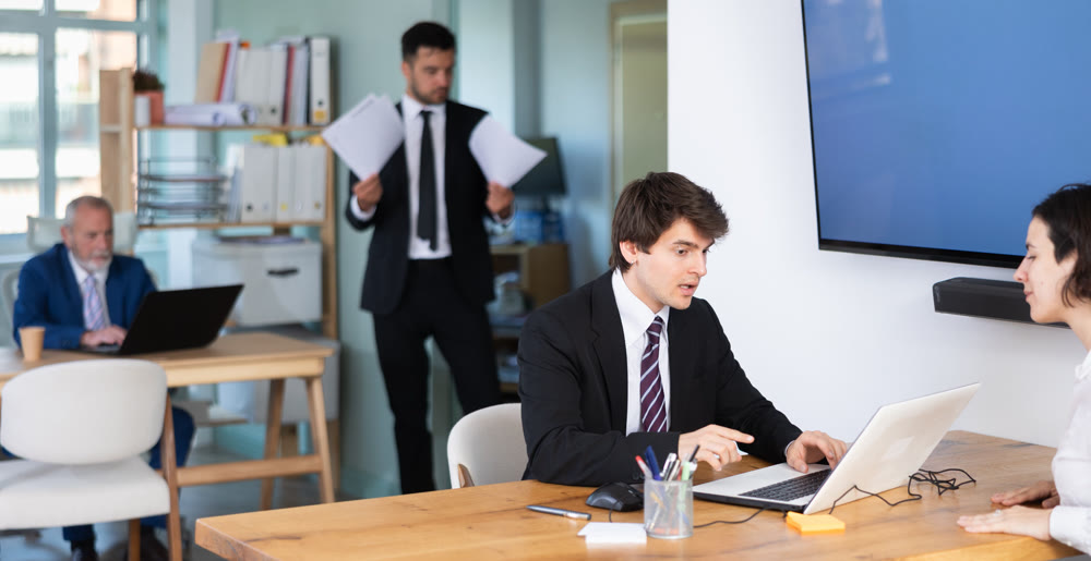 Professional young guy bank employee talking and signing loan agreement with young woman client in bank office