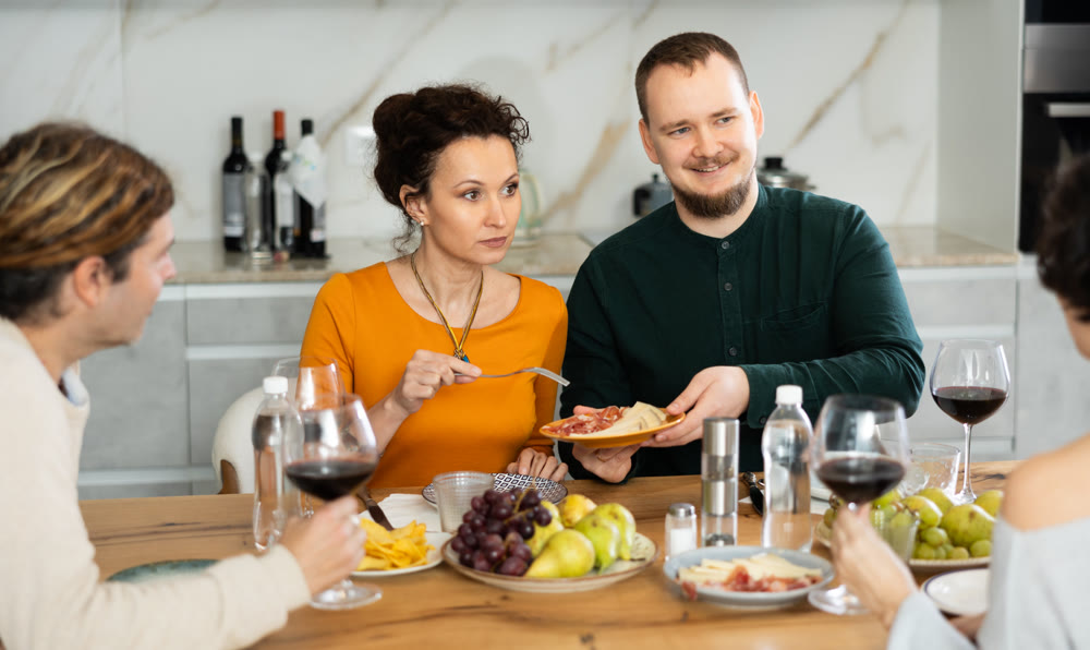 Group of joyful individuals are celebrating a holiday, enjoying drinks and conversation around table in their home