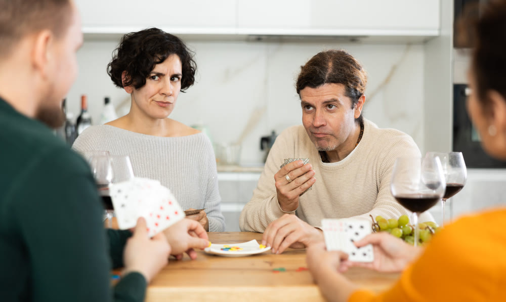Happy group of friends playing poker cards and drinking wine