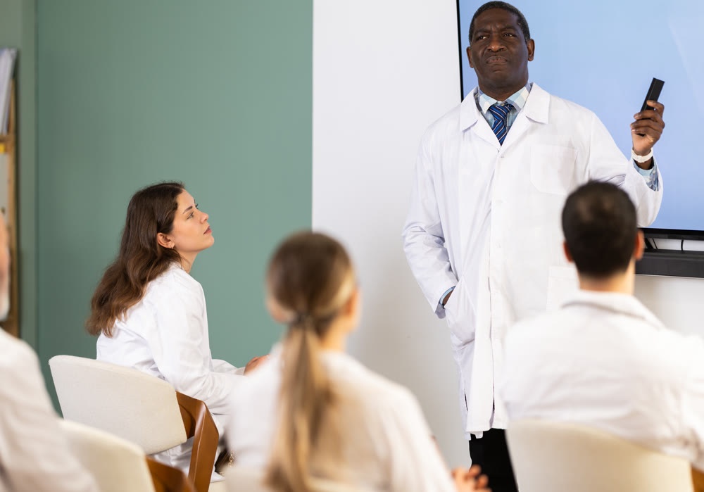 Adult male doctor presenting with remote control in meeting room