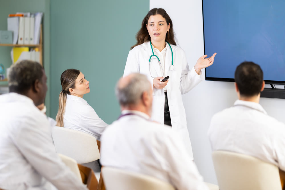 Young woman doctor with remote control giving lecture