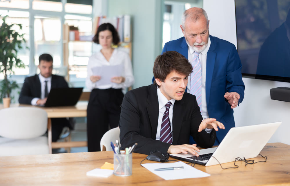 Bank employees look at the laptop screen and check the accounting
