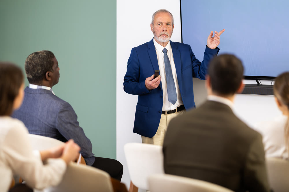 Eldery man presenting with remote control in meeting room