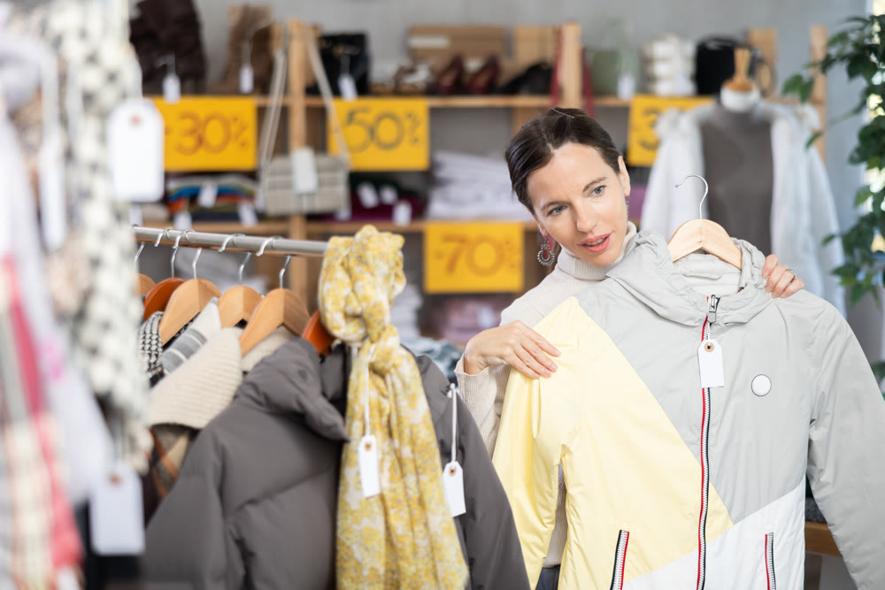 Adult woman choosing down jacket in clothing store