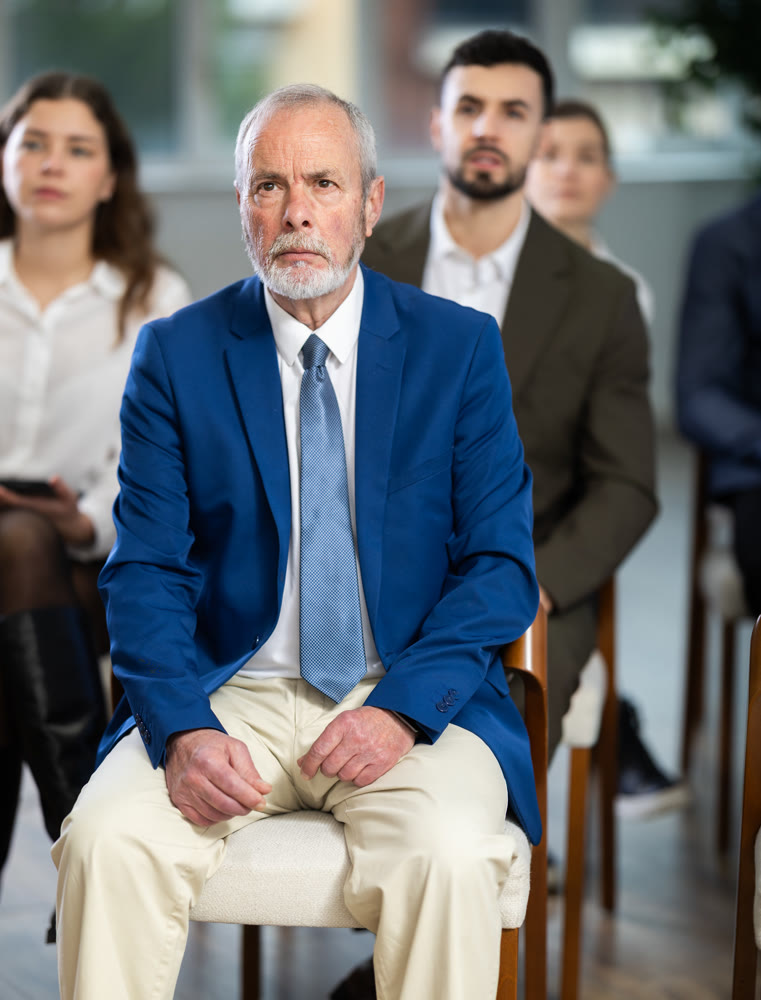 elderly man listens to a speaker at a conference on finance