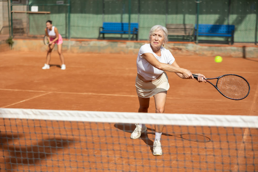Young woman playing tennis with older woman