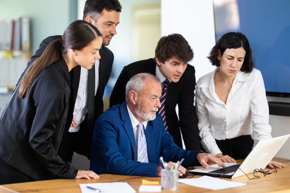 Senior man employee shows his colleagues photos from vacation