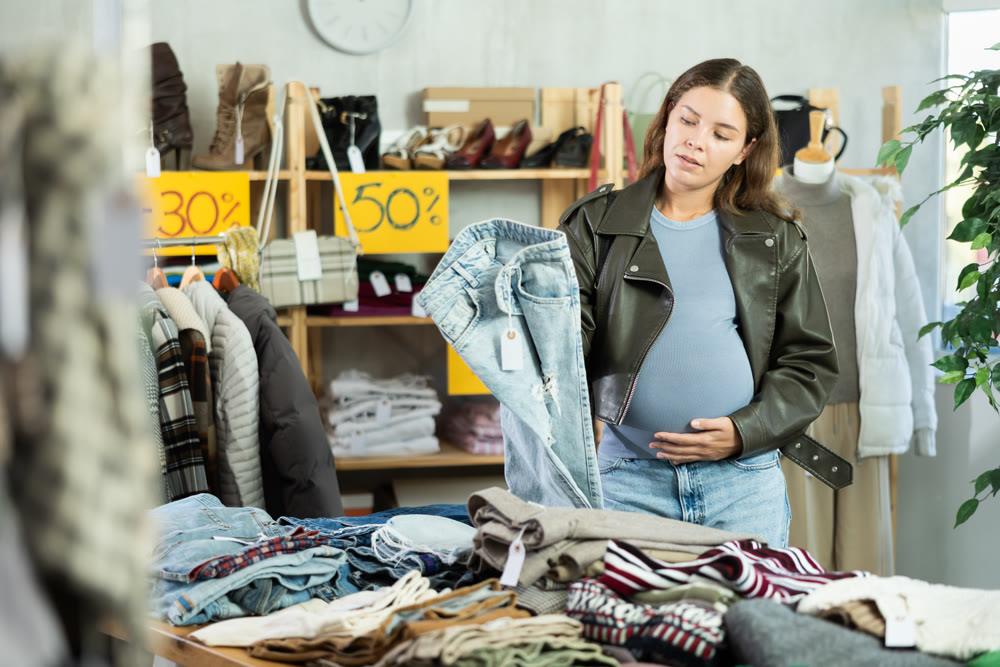 Pregnant woman choosing jeans in clothing store