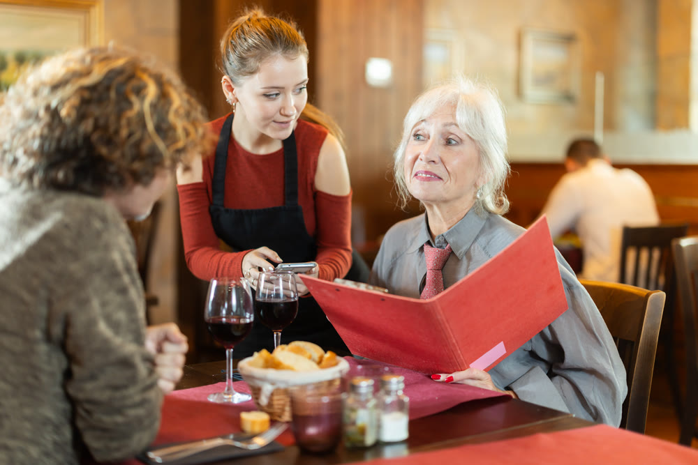 Waitress takes order from couple elderly woman and adult man