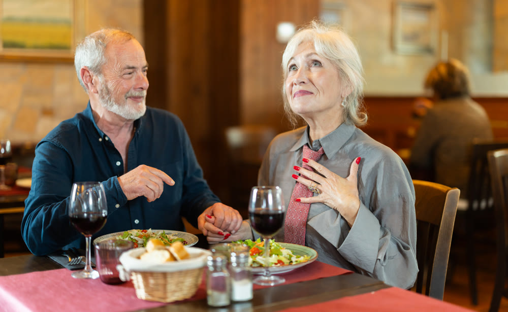 Elderly couple eating and talking in restaurant