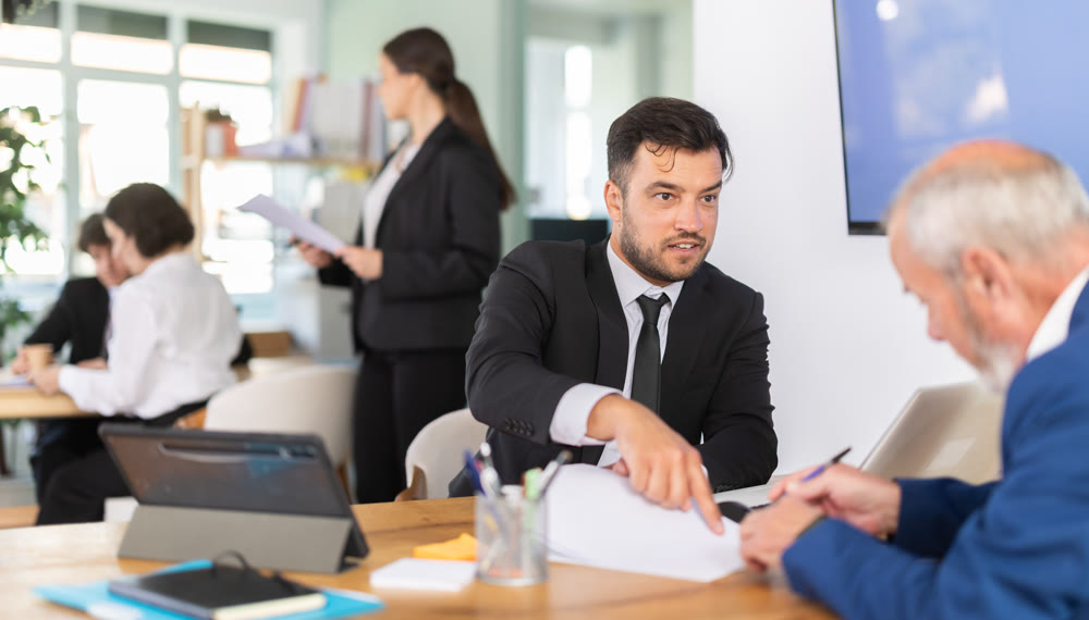 Man bank employees discussing financial documents and opening a deposit.