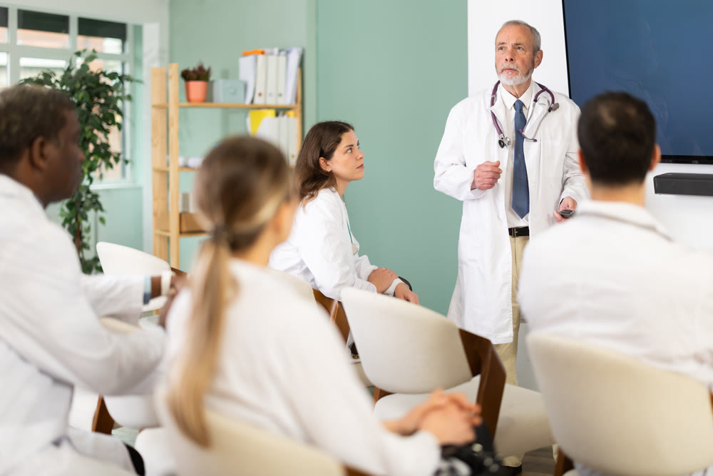 Eldery male doctor presenting with remote control in meeting room