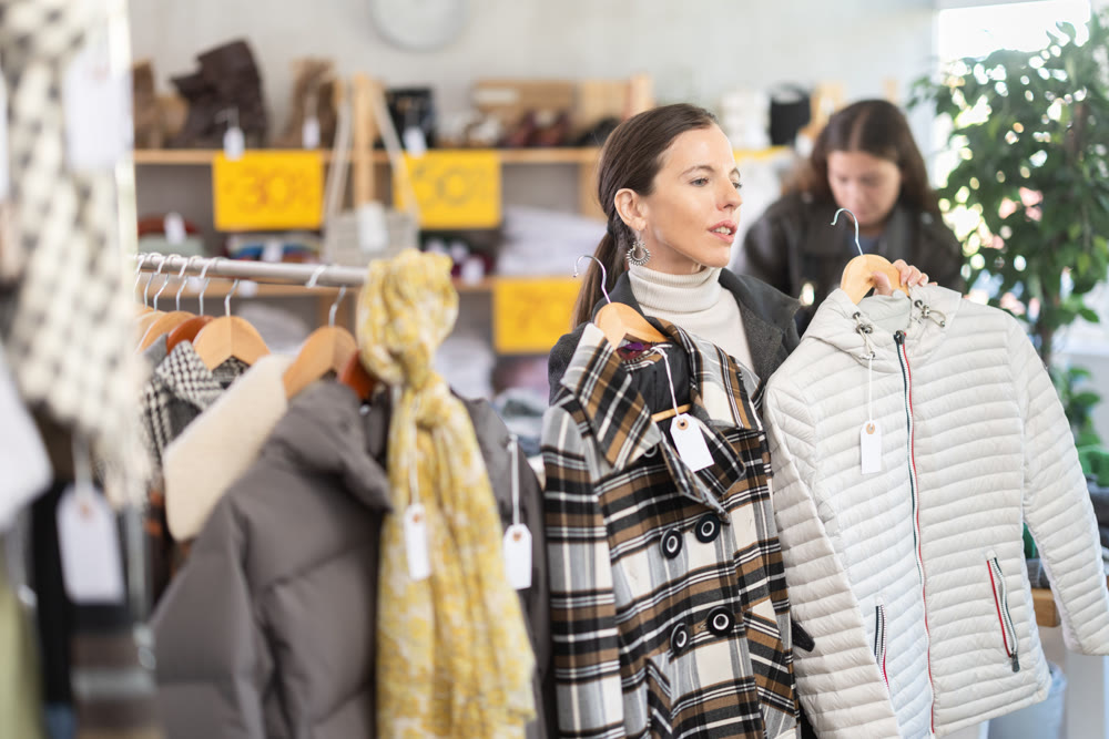 Selective middle-aged woman choosing something for autumn-winter in clothing store