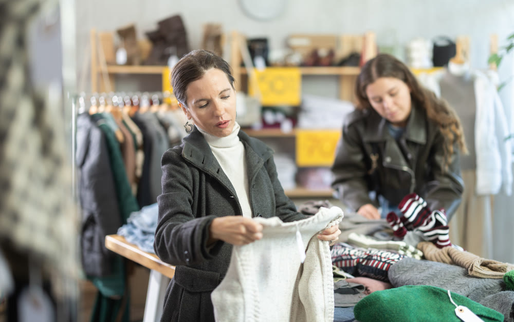 Adult woman chooses sweater in clothing store